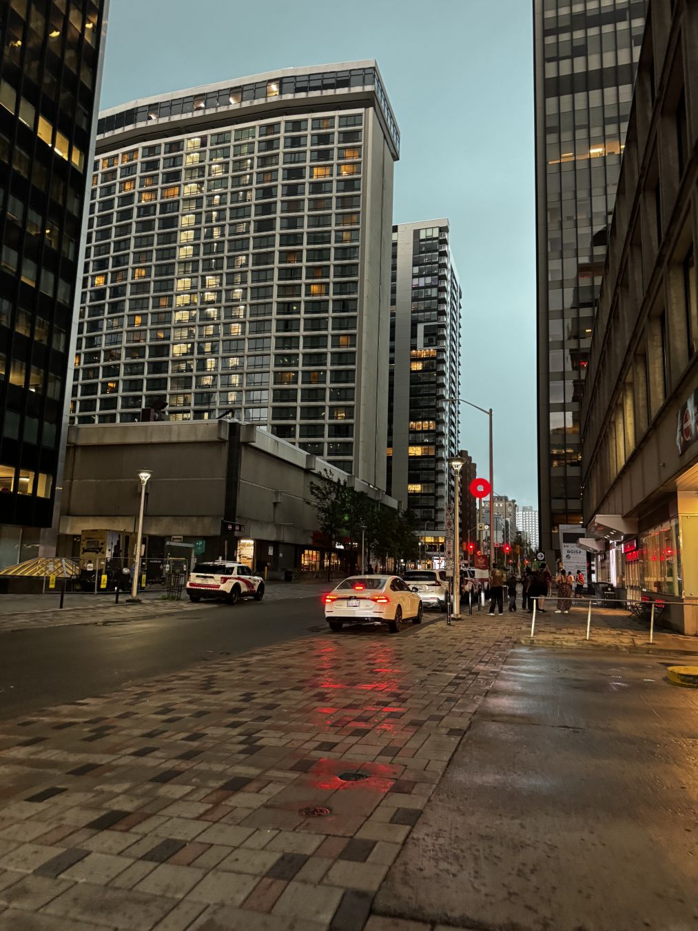 Queen St next to Lyon station around 17:00 EDT. All the lights illuminated because of the dark sky. 

The picture has a very dramatic tone, because it's about to pour down.
- - -
La rue Queen à côté de la station Lyon vers 17h HAE. Toutes les lumières sont allumées à cause du ciel sombre.

L'image a un ton très dramatique, car un déluge est sur le point de s'abattre.